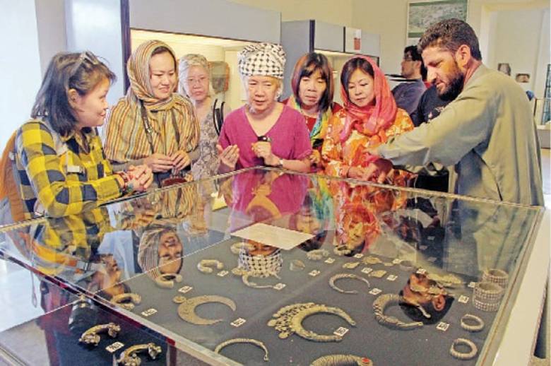 Thai tourists being briefed about Buddhist artefacts at Swat Museum on Wednesday.   Dawn